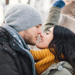 A happy young man and woman kissing in winter enjoying life and